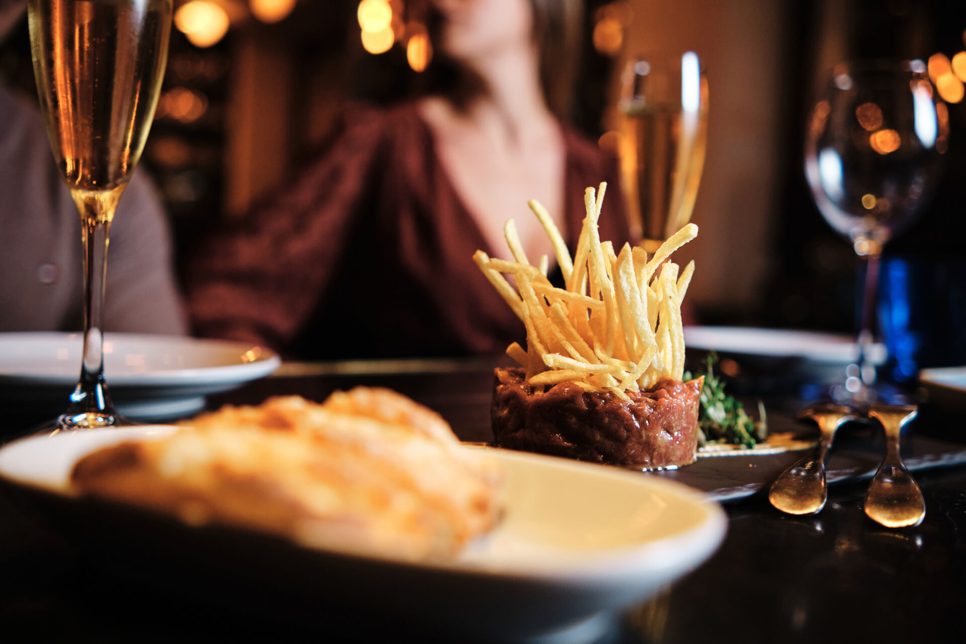 Close-up of a delicious gourmet meal plate and beverage glasses on table with a couple at background. Couple having a meal at restaurant.