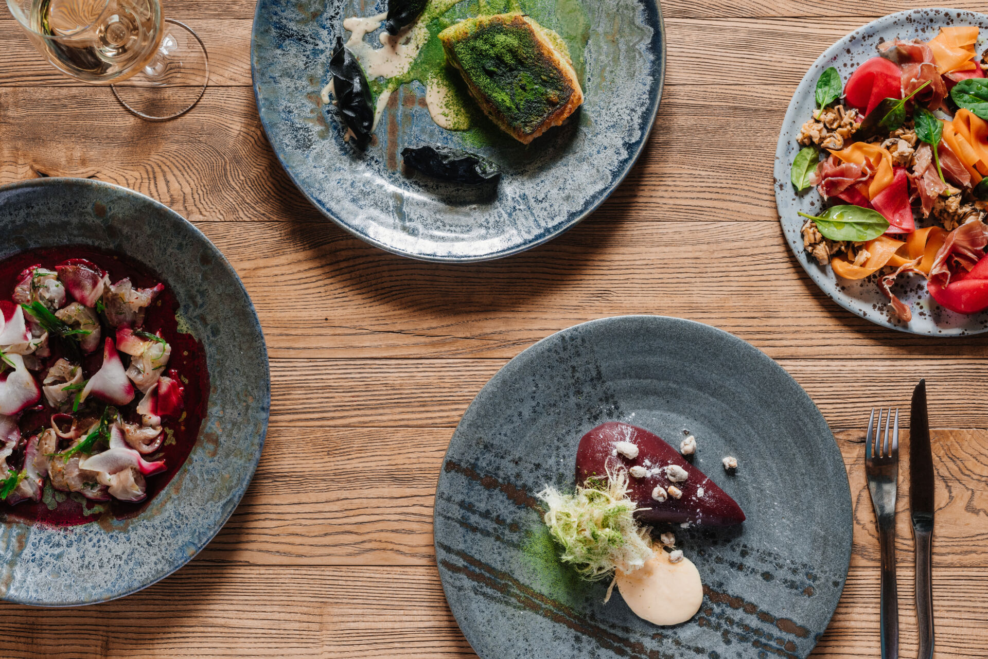 top view of delicious dishes and glass of wine on wooden table